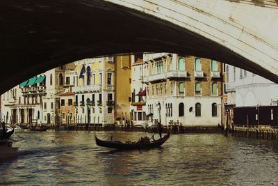 Gondolier in gondola at grand canal seen from arch of rialto bridge