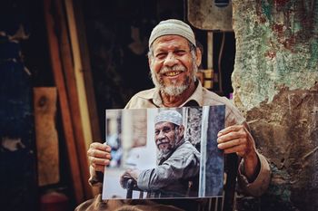 PORTRAIT OF HAPPY MAN HOLDING CAMERA