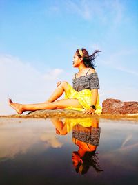 Woman with arms outstretched against sky