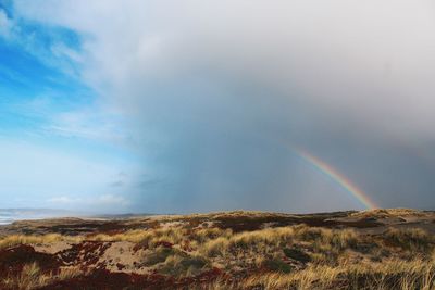 Scenic view of rainbow over mountain against sky