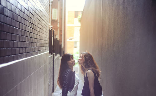 Portrait of woman standing with female friend puckering at alley