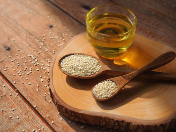 White sesame seeds in wooden spoon and a glass of sesame oil for healthy food concept.