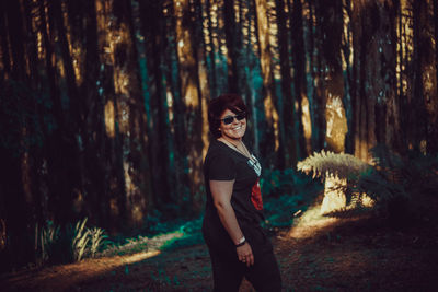 Portrait of smiling young woman standing in forest