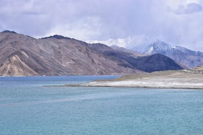 Scenic view of lake by mountains against sky