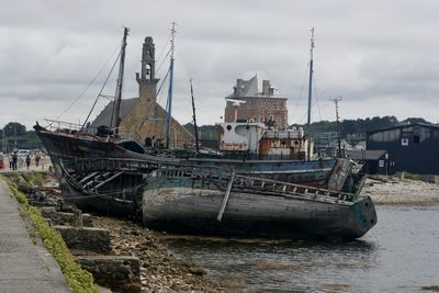 Abandoned boat moored at harbor against sky