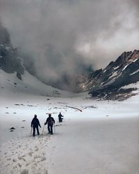 People walking on snowcapped mountain against sky