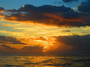 Scenic view of sea against dramatic sky during sunset