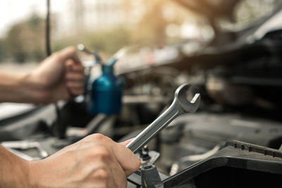 Cropped image of person repairing car engine