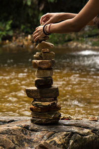 Cropped hands stacking stones by river