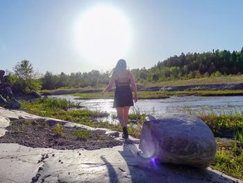 Rear view of woman standing on rock against sky