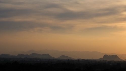 Scenic view of silhouette mountains against dramatic sky