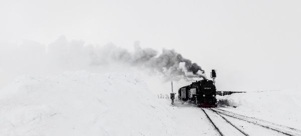 Train on railroad tracks against snowcapped mountains during winter