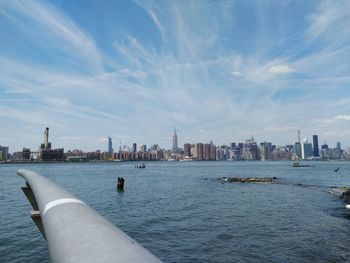 View of city at waterfront against cloudy sky