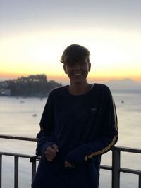 Portrait of young man standing against sky during sunset