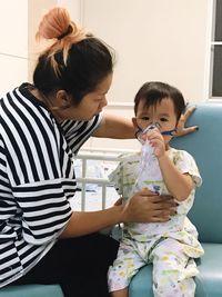 Mother sitting by son using oxygen mask while sitting in hospital