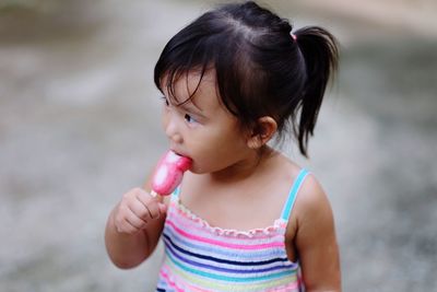 Cute girl eating ice cream while standing on street