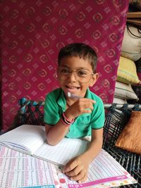 Portrait of cute boy sitting on bed at home