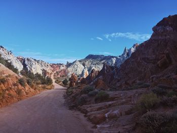 Road amidst mountains against blue sky