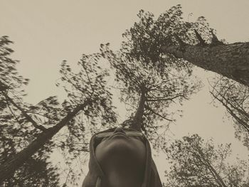 Low angle view of woman against trees against sky