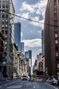 View of city street against cloudy sky