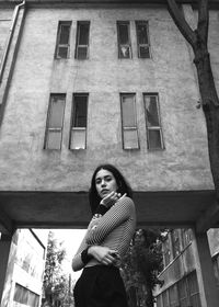 Low angle portrait of woman standing against building