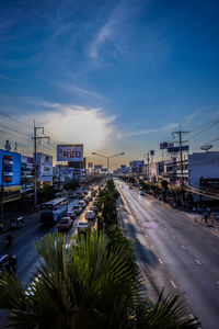 Road by buildings in city against sky