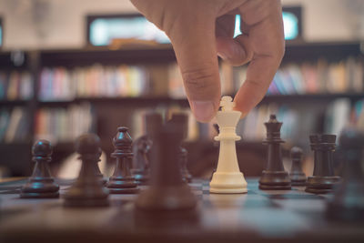 Cropped hand playing chess in library