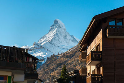 Houses by snowcapped mountains against clear sky