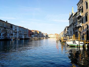 Canal amidst buildings in city against sky