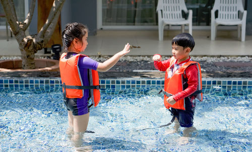 Full length of happy friends enjoying in water
