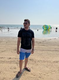 Young man in casual clothes standing at beach 