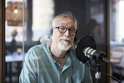 Mature man sitting and hosting podcast or radio show or podcast