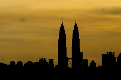 Silhouette petronas tower against orange sky