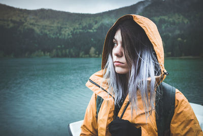 Young woman looking away against lake