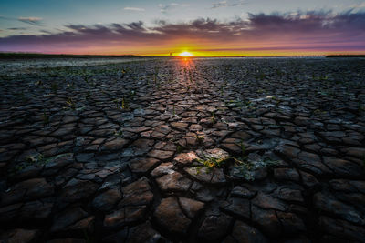 Scenic view of cracked land during sunset