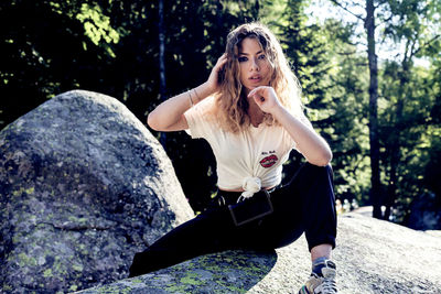 Portrait of young woman sitting on rock