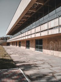 Empty road by building in city against sky