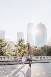 Man and woman walking on road against buildings