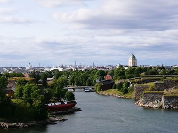 Boats in river by cityscape against sky