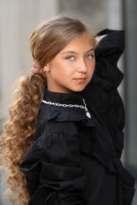 Portrait of girl standing against black background