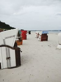 Hooded chairs on beach against sky