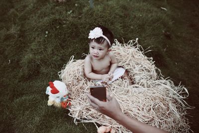 High angle view of topless baby girl sitting on straw at field