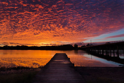 Jetty over lake against orange sky