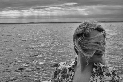 Rear view of woman at beach against sky