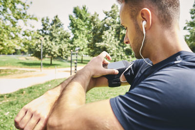 Midsection of man using mobile phone against trees