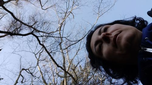 Low angle portrait of girl against bare tree