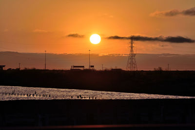 Silhouette electricity pylon against sky during sunset