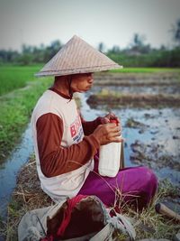 Full length of man sitting on field by lake