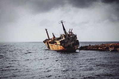 Abandoned ship in sea against sky