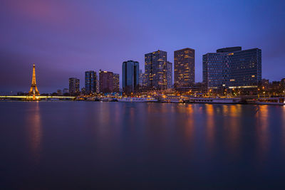 Illuminated city by buildings against sky at night